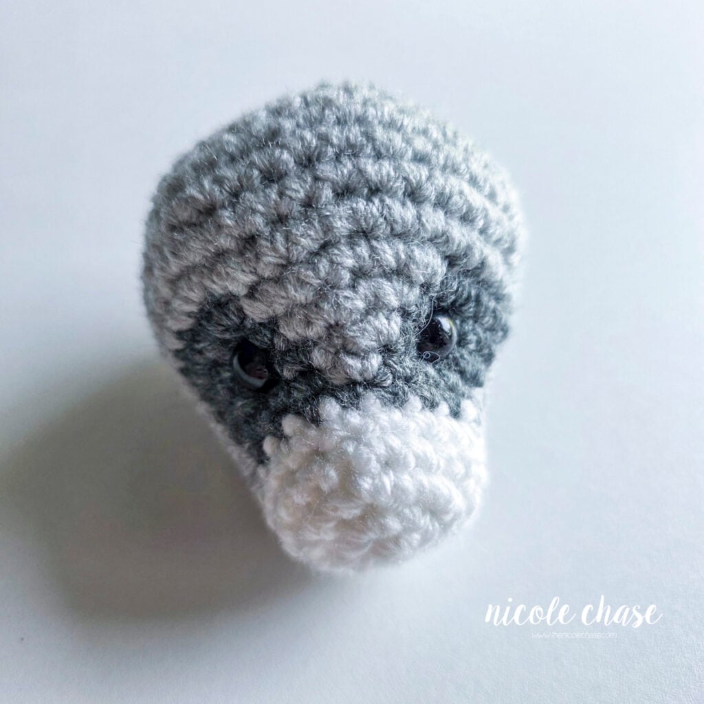 Finished head of the raccoon amigurumi that is filled with stuffing and awaiting assembly. 