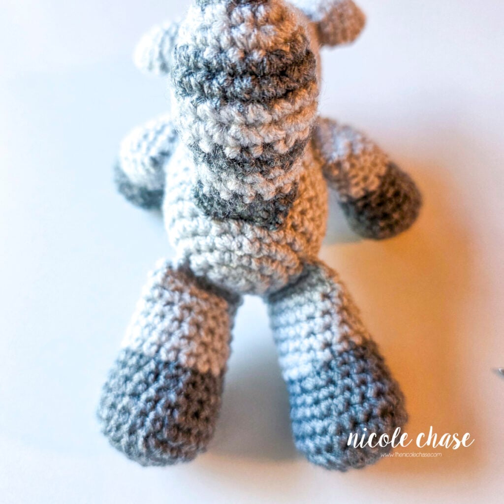The striped crochet tail has been sewn into place on the back of the body. 