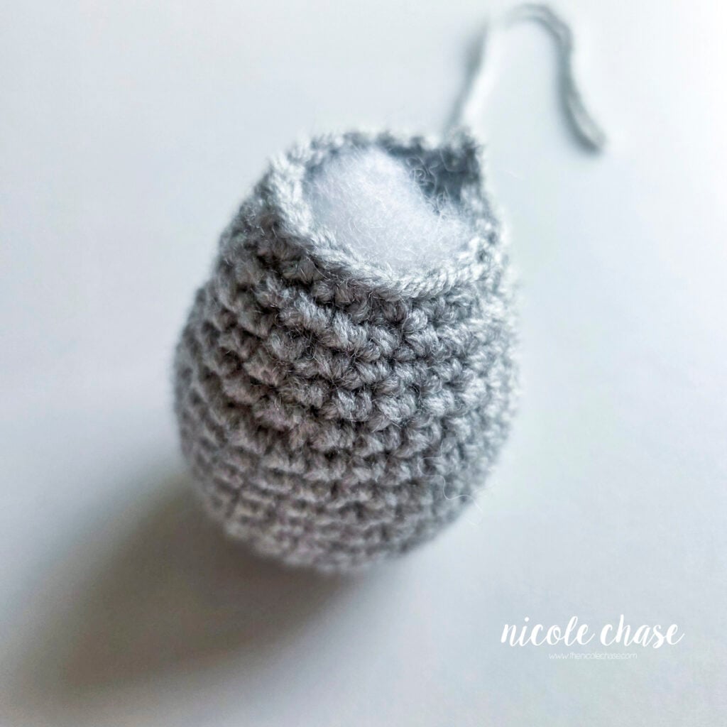 The finished body of the crochet raccoon made in a light gray yarn and filled with poly-fil stuffing. 